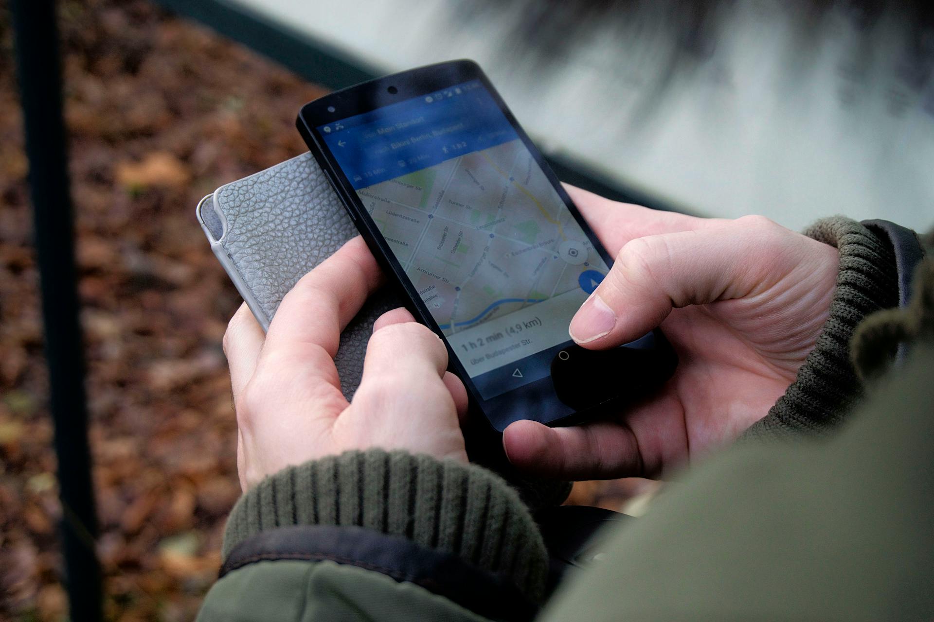 Hand haelt Smartphone mit Karten-App im Freien